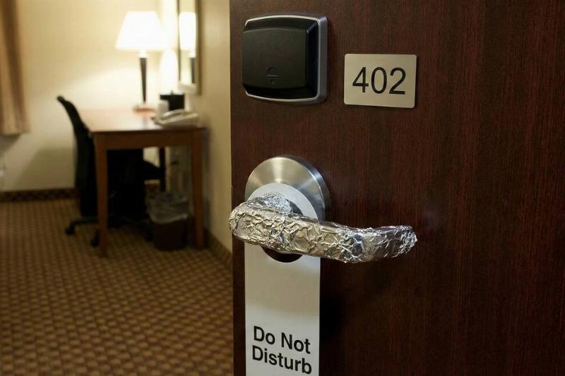 A hotel room door handle that has been covered with aluminum foil. 