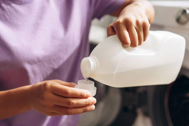 Hands pouring vinegar into measuring cup. 