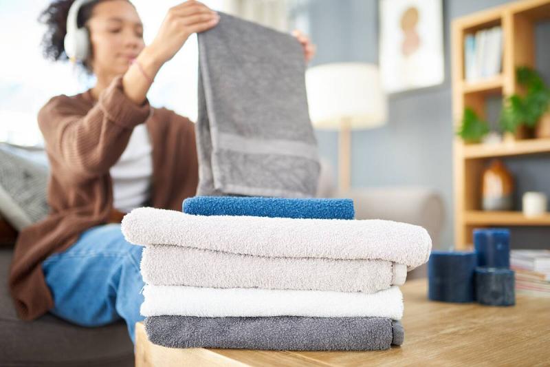 Woman folding towels with a border. 