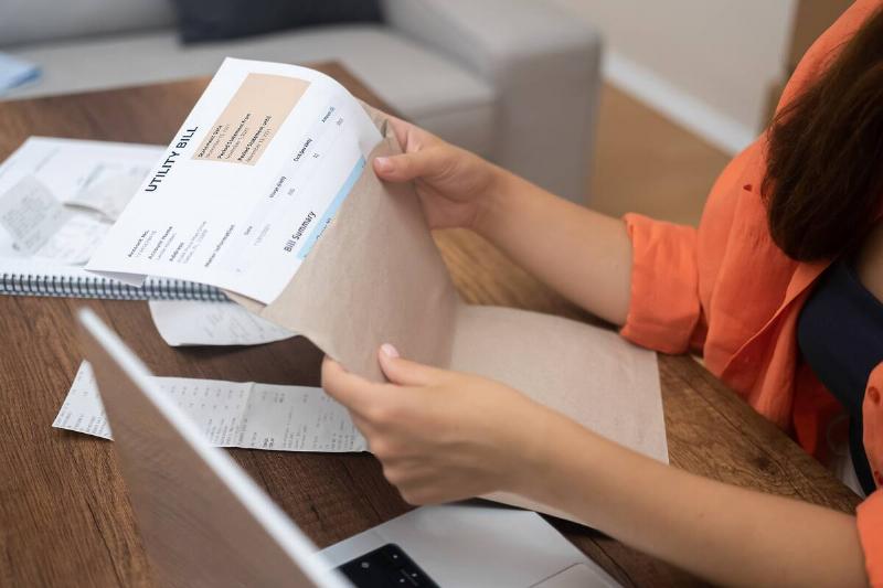 Woman taking bill out of envelope. 