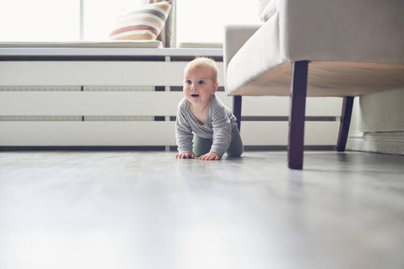 A baby crawling on the floor. 