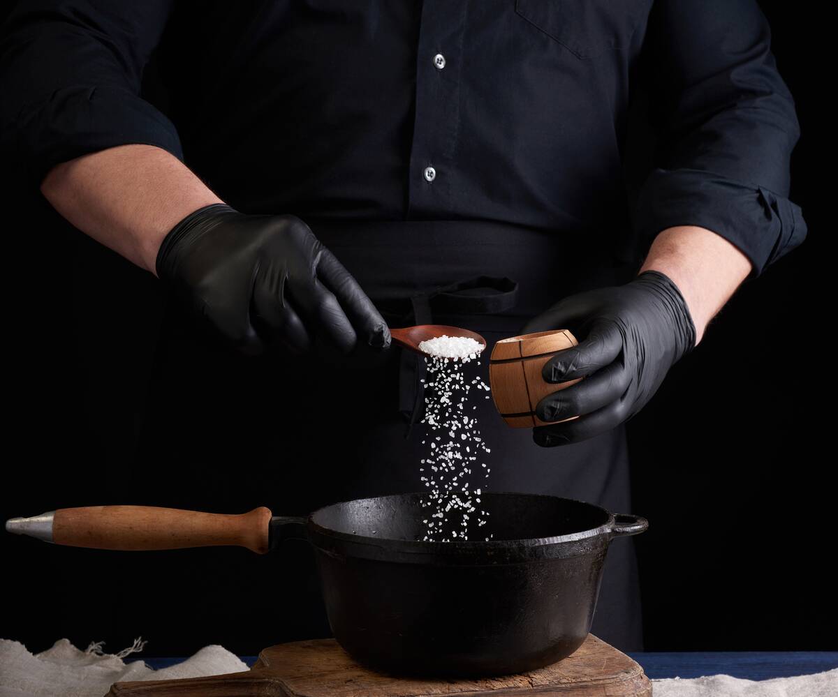 Man putting salt on cast iron pot. 