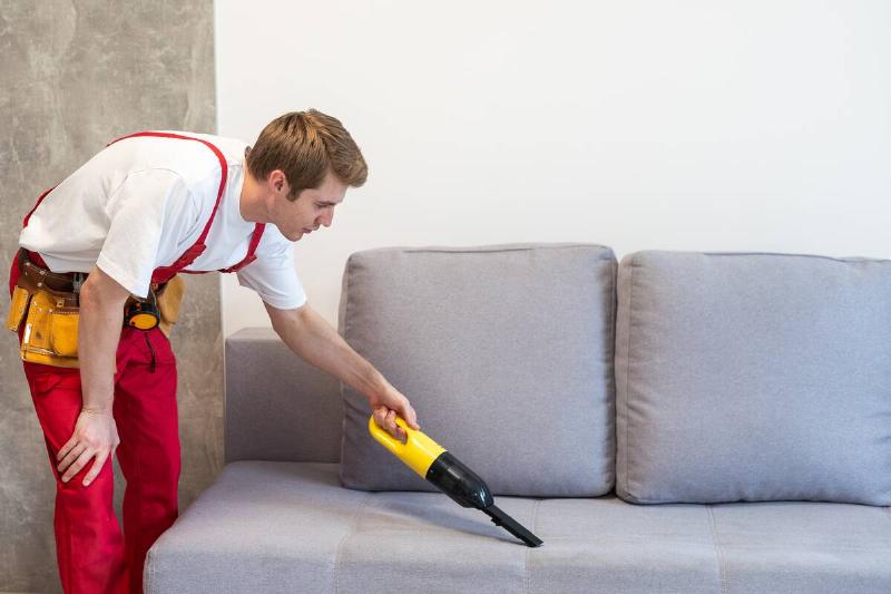 A professional cleaner cleaning a couch. 