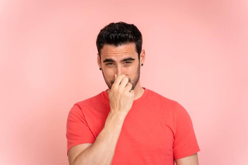 Man plugging nose against bad smell. 