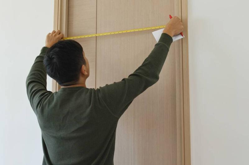 Man measure the size of a door.