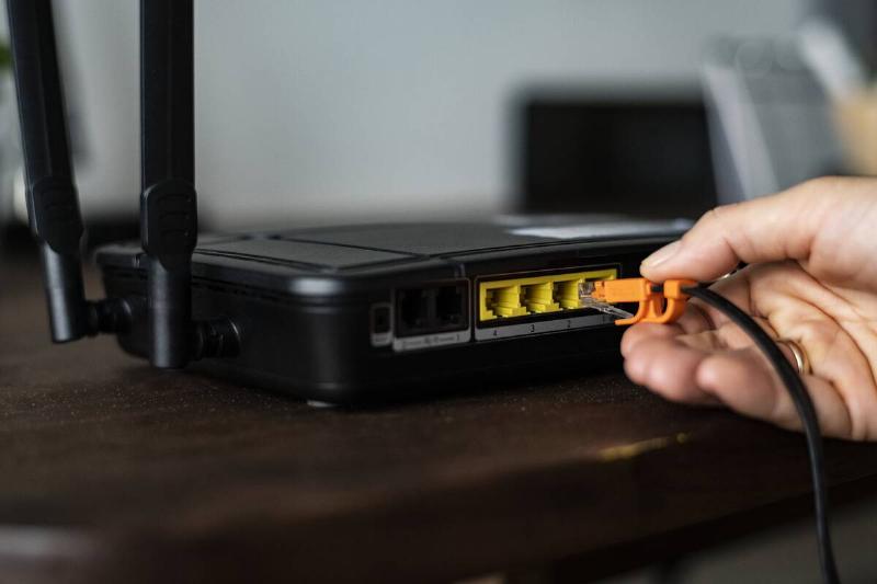 Man plugging in an ethernet cable to a wireless router.