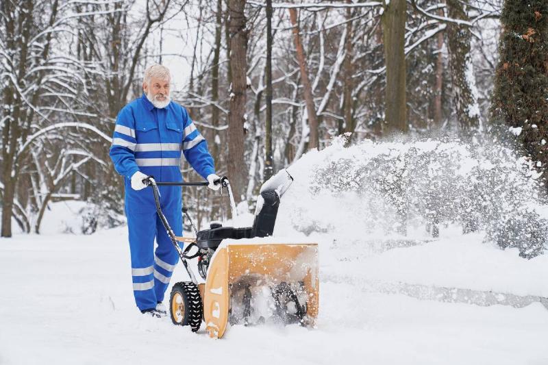 Senior man using snow blower. 