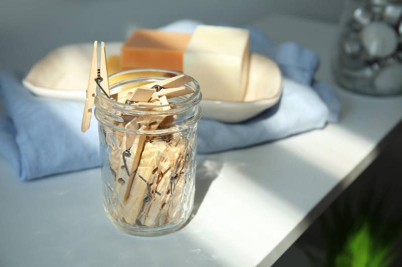 Wooden clothespins inside of a glass jar. 