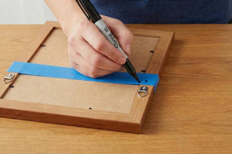 A person making markings on the tape on the back of the frame. 