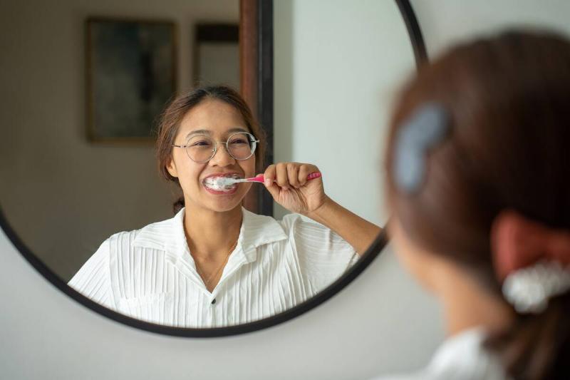 Young woman brushing teeth with toothbrush.