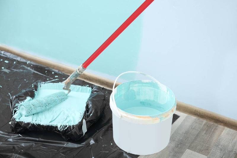 Paint roller for interior decorating with bucket of paint on the floor in a room.