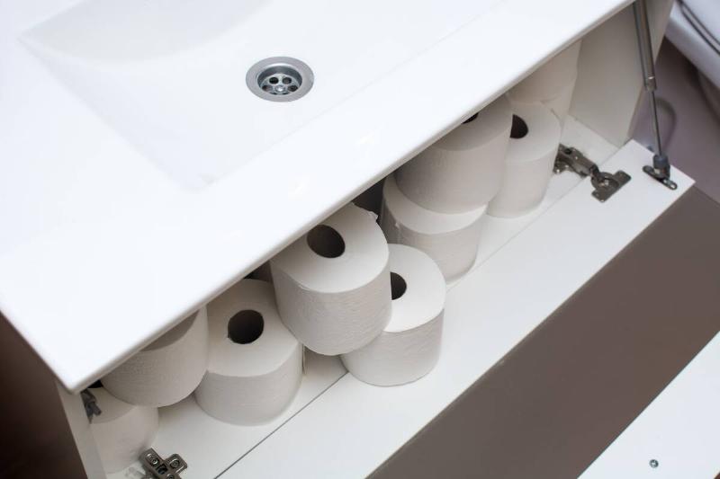 Toilet paper stored under a bathroom sink. 