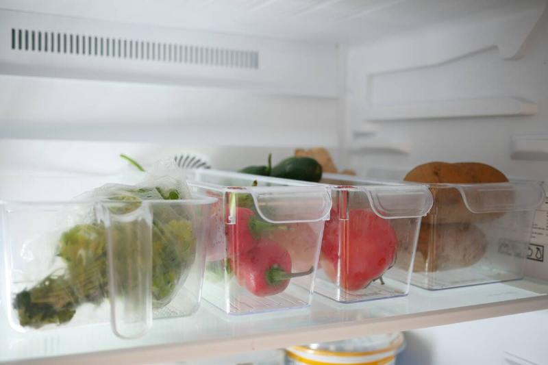Plastic containers in a fridge, holding vegetables. 