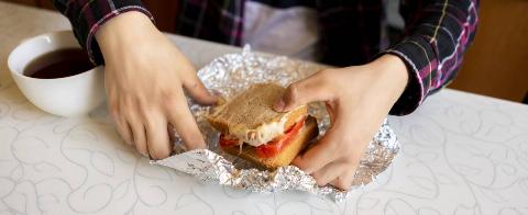 Person eating a sandwich out of foil. 