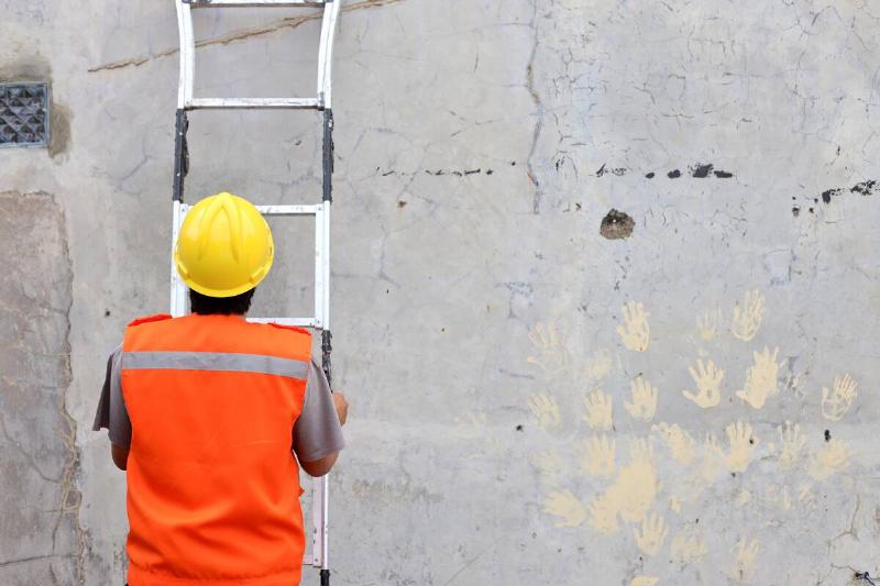 Man leaning ladder against wall. 