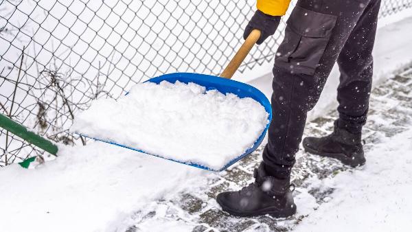 Person shoveling snow on sidewalk. 