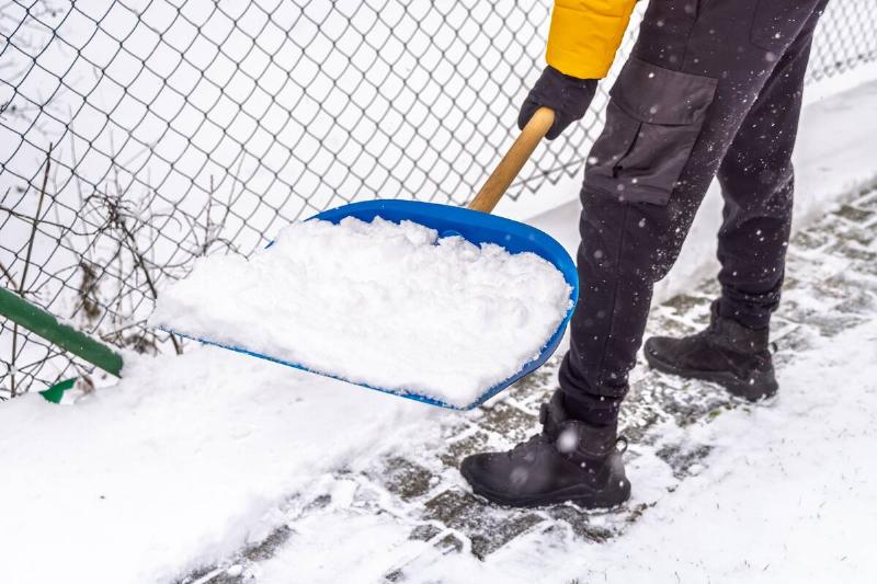 Person shoveling snow on sidewalk. 