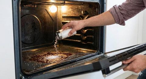 A person sprinkling salt in their oven. 