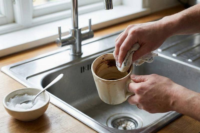 A person cleaning a mug with salt.