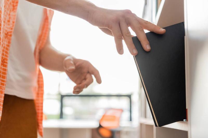 Person putting book on shelf. 