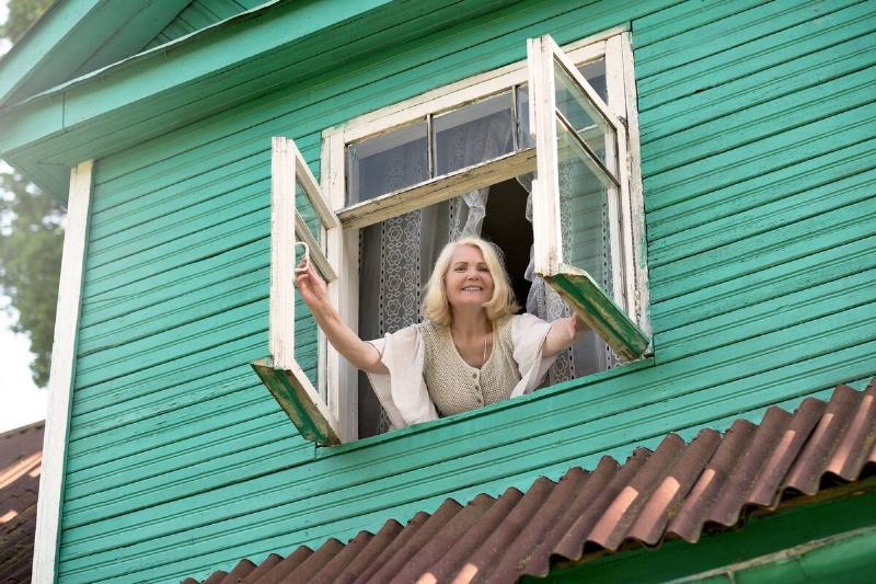 Woman opening windows of house. 