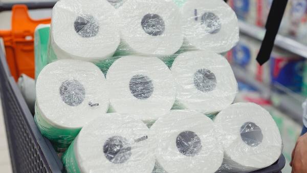 Shopping trolley full of toilet paper packs in supermarket.