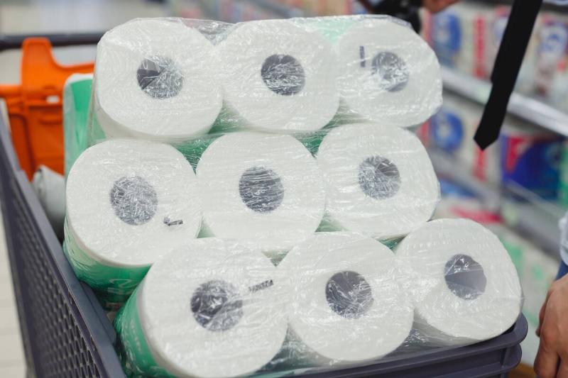 Shopping trolley full of toilet paper packs in supermarket.