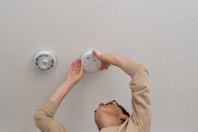 Person replacing smoke detector in their house. 
