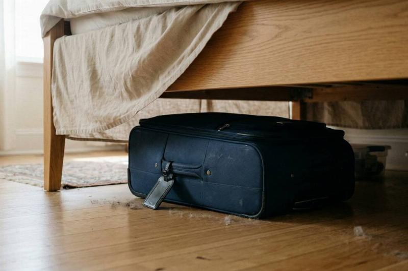 A suitcase stored under a bed.