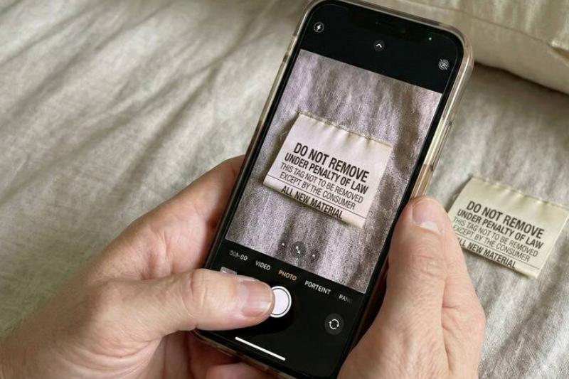 сфотографировать метку Человек фотографирует бирку, отрезанную от подушки.