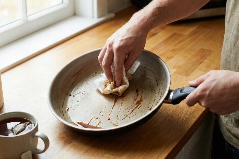 A person wiping black tea all over a pan. 