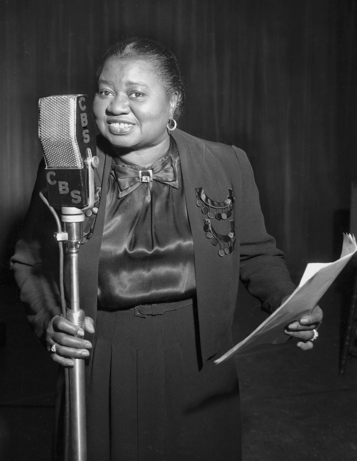 Hattie McDaniel standing at a microphone, holding a script