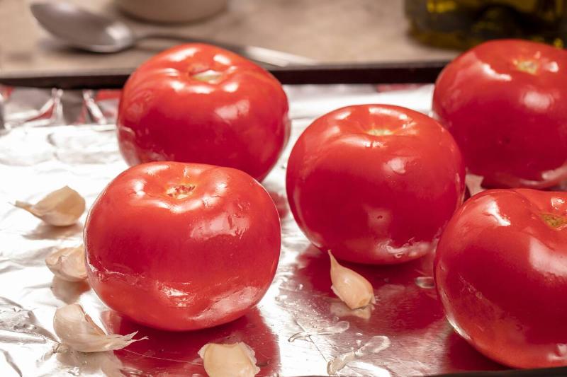Tomatoes and garlic on foil sheet. 