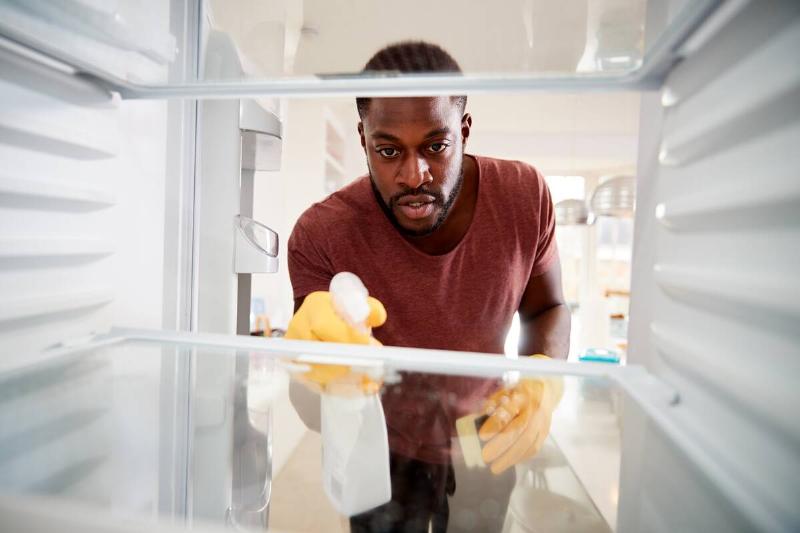 A man cleaning the inside of a fridge. 