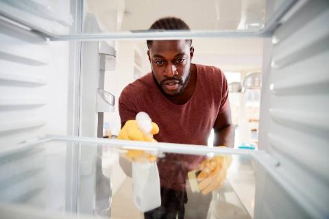 A man cleaning the inside of a fridge. 