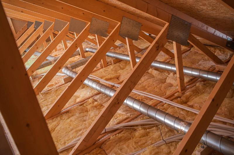 Construction work shows wooden beams and insulation in an attic area.