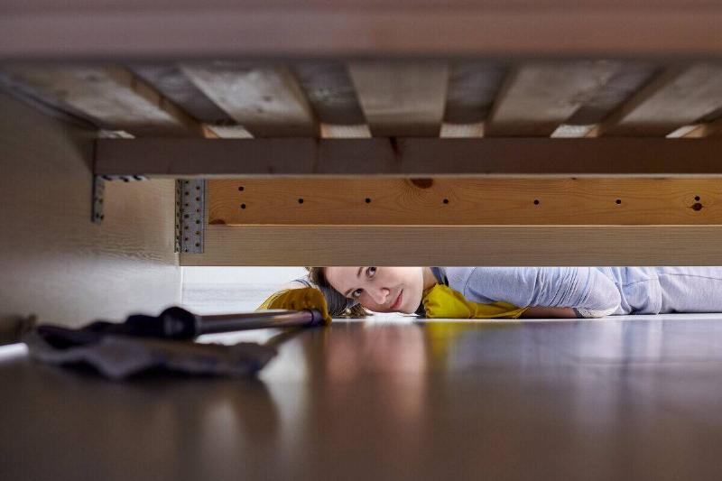 Woman trying to reach something under a couch. 