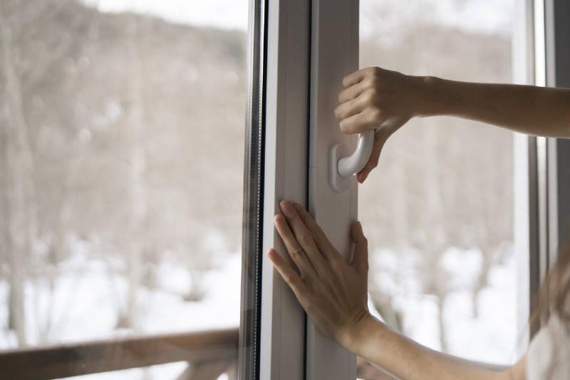 A  woman is seen opening a window in her home.