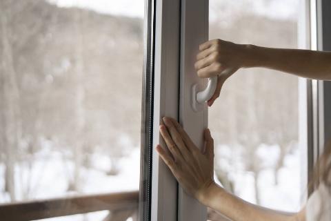 A  woman is seen opening a window in her home.