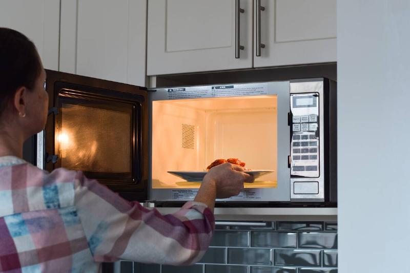 Woman putting food in microwave.