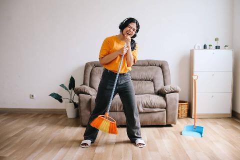 Woman singing into a broom like a microphone. 