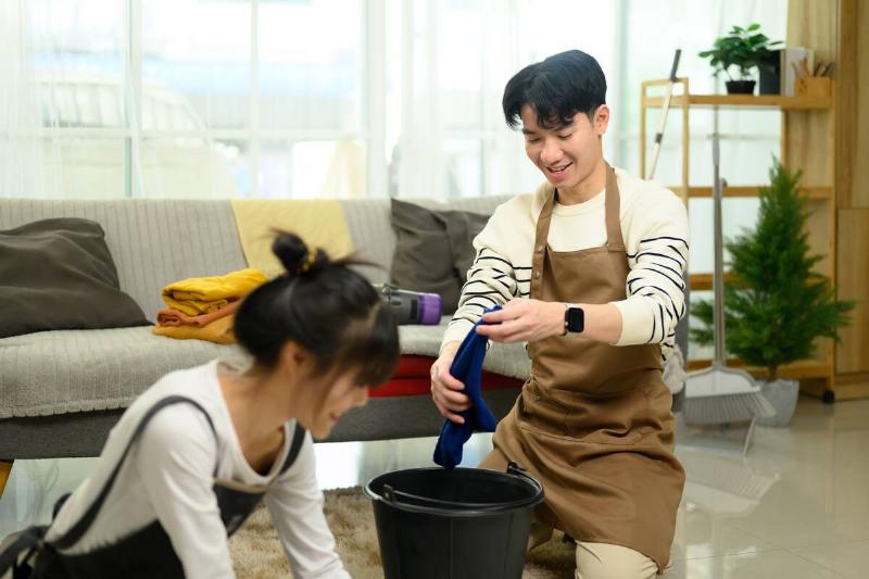 Young couple enjoys cleaning their home washing floor together.