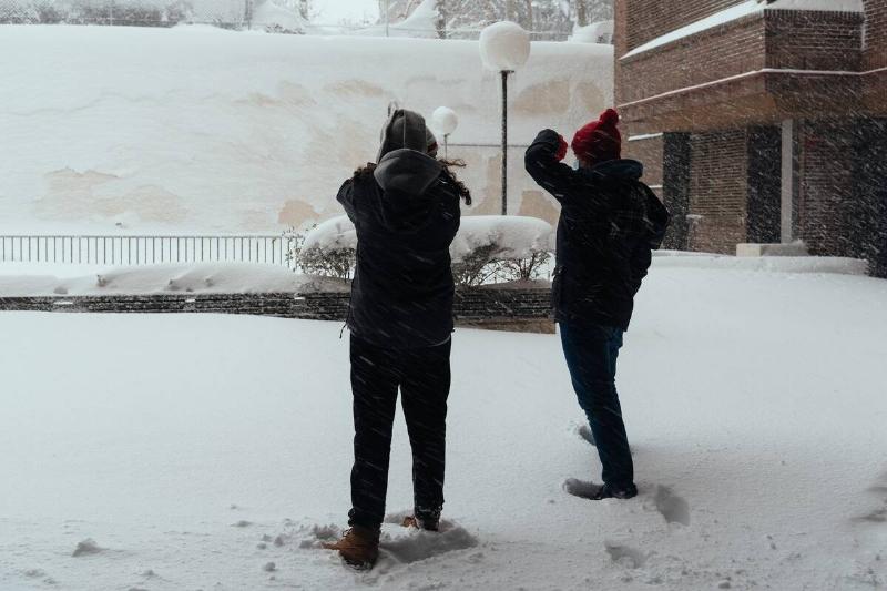 Two people talking in the street in the middle of a snowstorm.