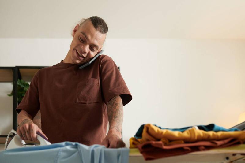 Man talking on the phone while ironing clothes. 