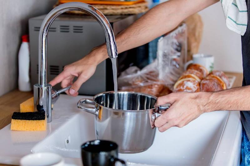 Person filling pot with hot tap water. 