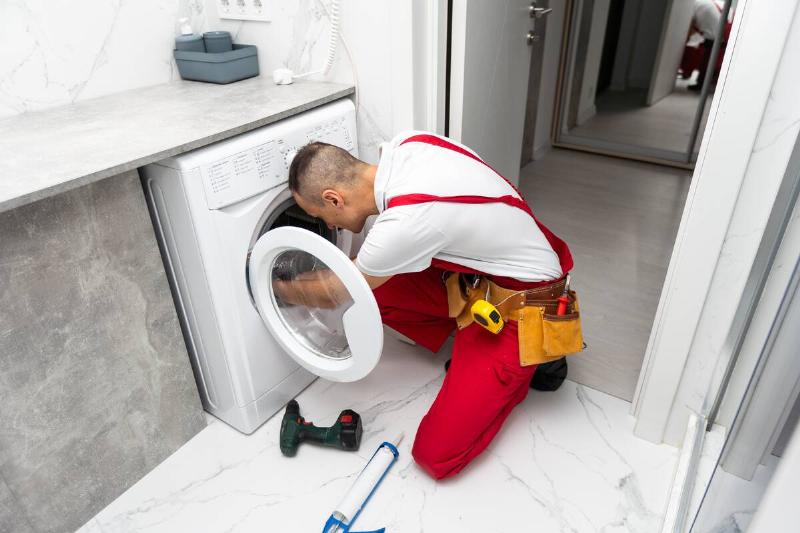 Plumber fixing a washing machine. 