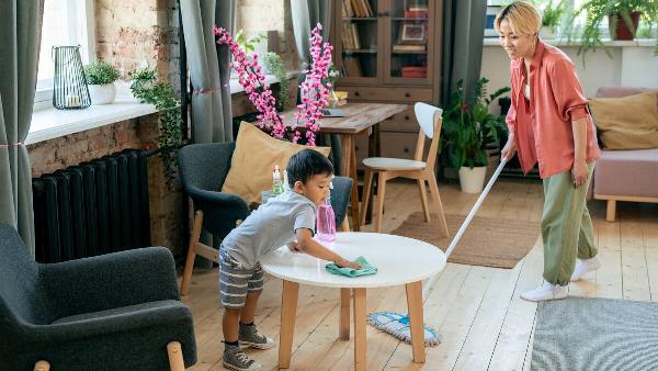 Woman and son cleaning living room. 