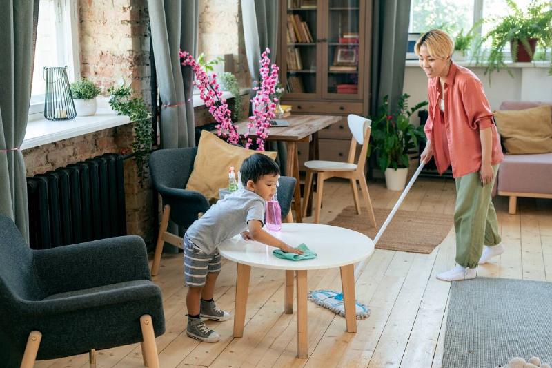 Woman and son cleaning living room. 