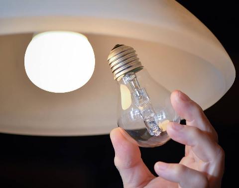 Hand replacing a lightbulb in a lamp. 