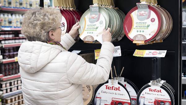 A woman chooses a non-stick frying pan in a Super U supermarket.